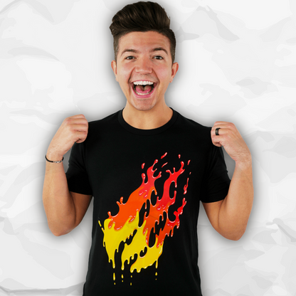 Preston Playz wearing a black t-shirt with a dripping red, orange, and yellow flame graphic, posing with his hands on the shoulders of the shirt against a crumpled white paper background.